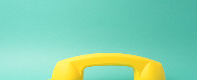 Cornetta del telefono gialla su fondo azzurro